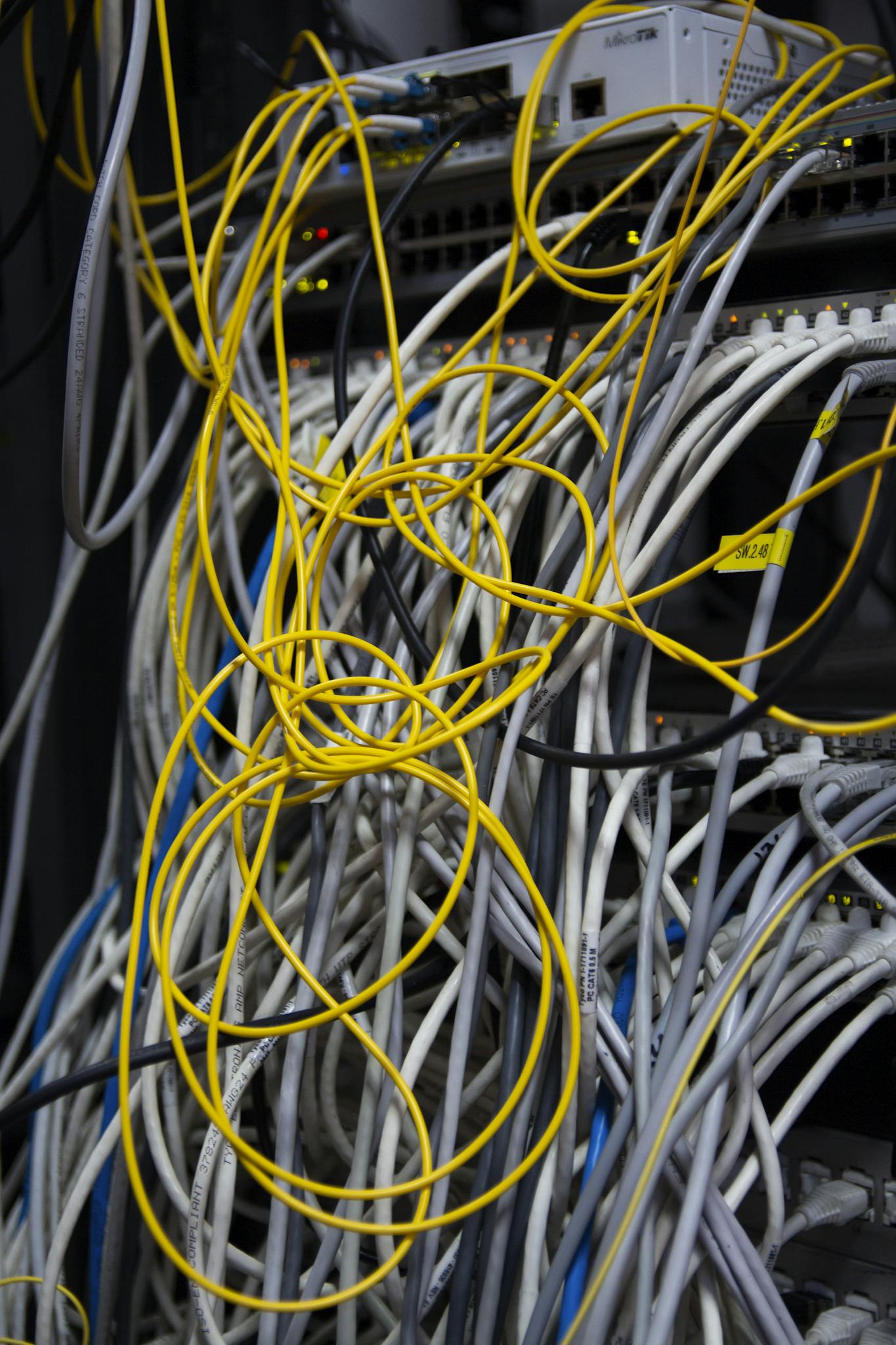 Close-up of a messy bundle of network cables tangled in a server rack.