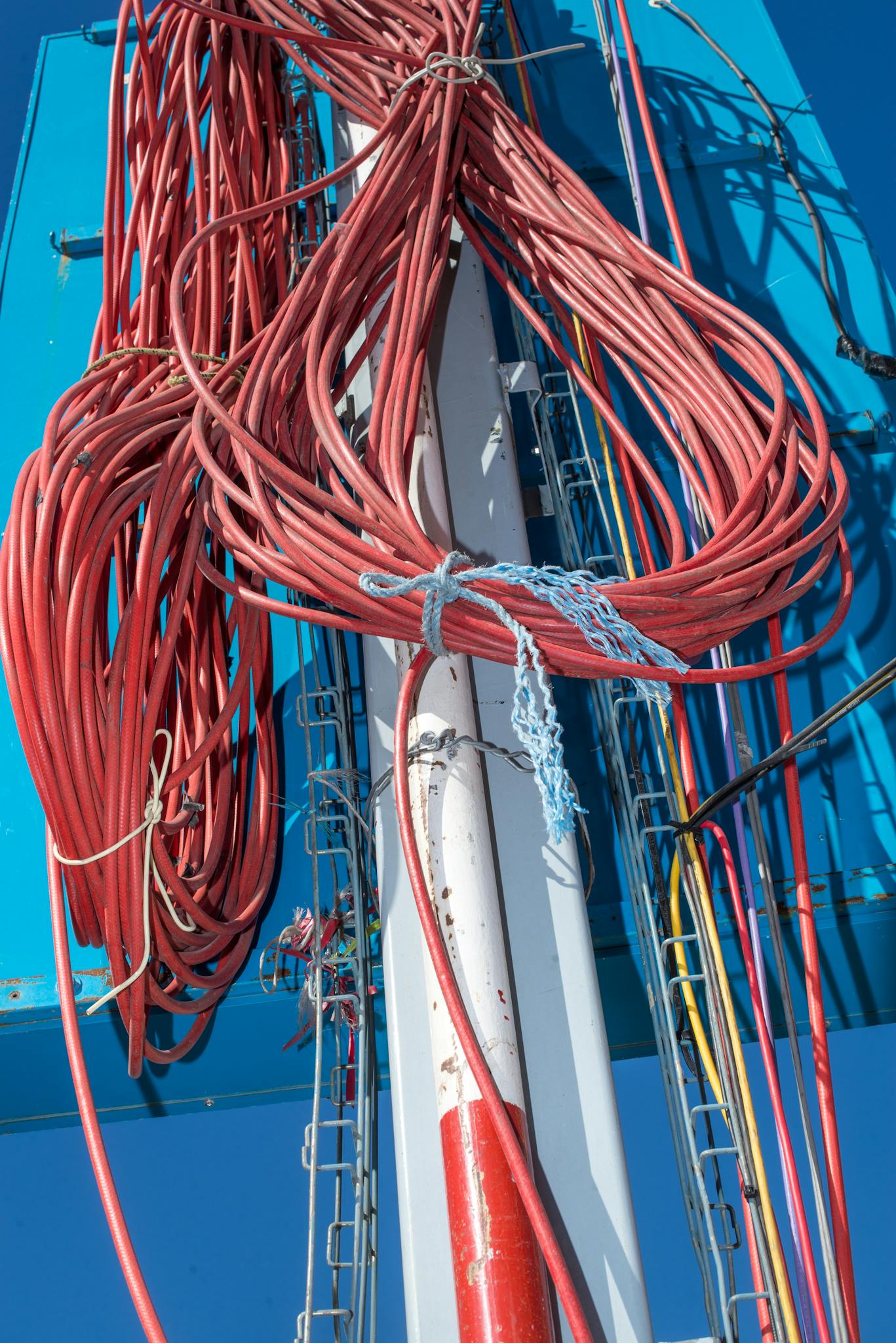 Close-up of vibrant cables on a communication tower against blue sky.